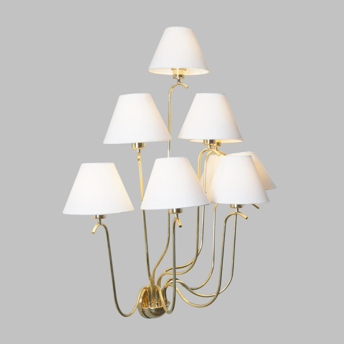 Modern classic brass multi-arm light fixture with tiered white shades designed for sophisticated interiors.