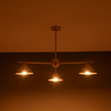 Handcrafted brass cone chandelier with three lights glowing softly in ambient warm lighting.