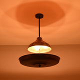 Modern copper disc chandelier suspended from ceiling, glowing softly in a dark ambient setting