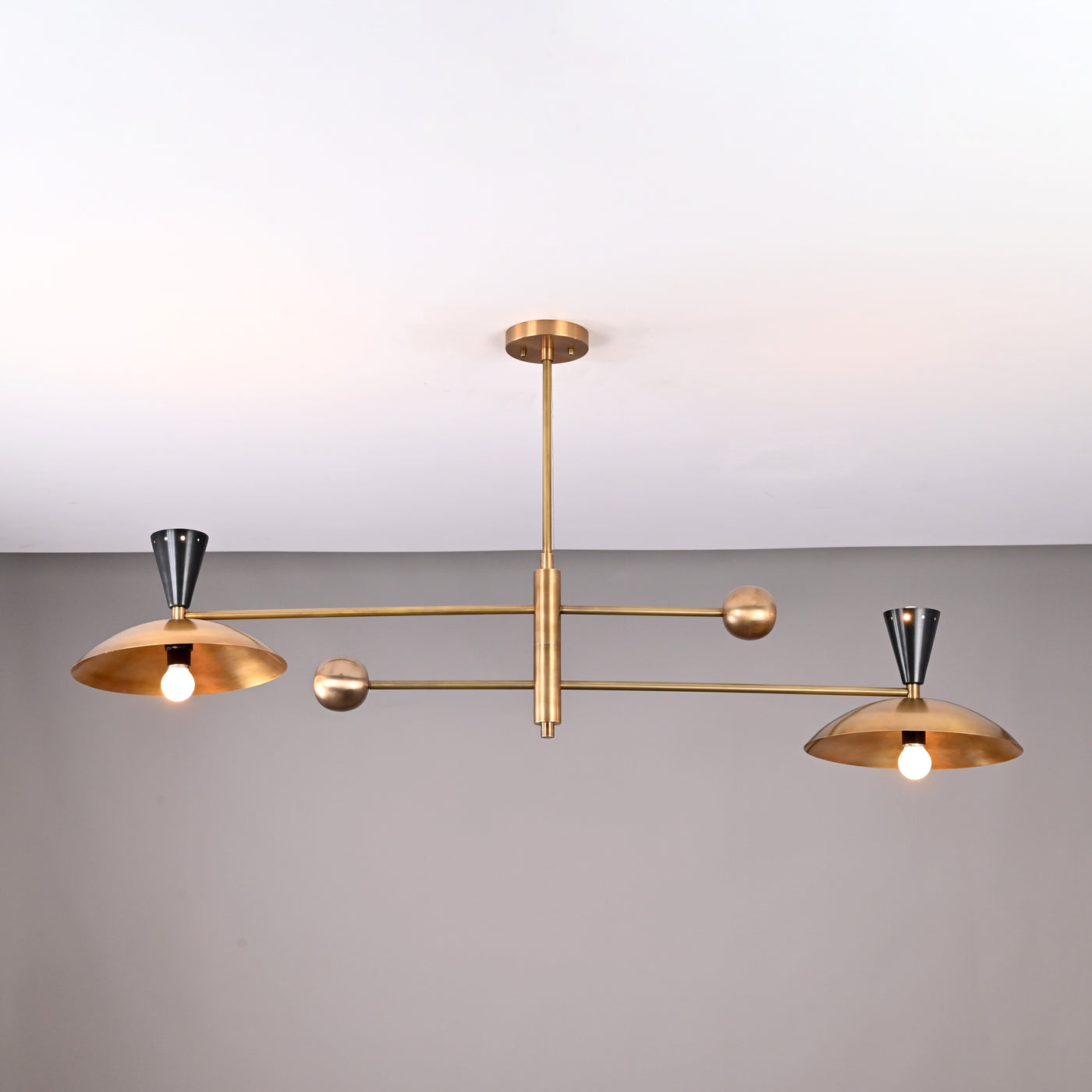 Front view of handcrafted 4-light Diabolo brass chandelier with brushed brass shades and contrasting black cone sockets.