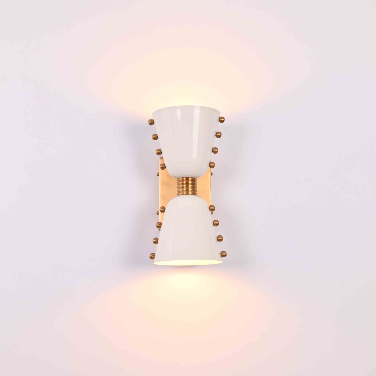 Modern diabolo wall sconce closeup showing white painted brass shades and brass hardware details