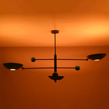 Modern disc chandelier glowing softly in dark setting with warm, atmospheric ceiling lighting