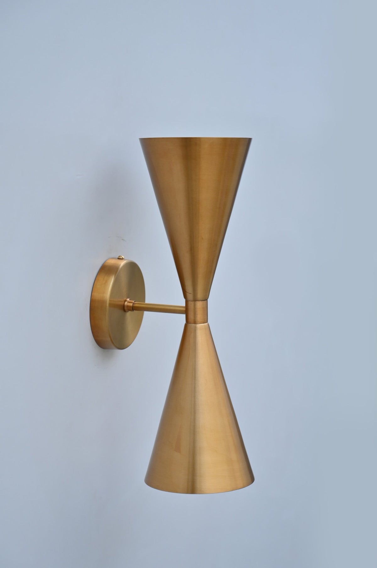 Side angle of modern brushed brass double cone wall sconce by Brass Leaf Studio showing smooth satin finish and elegant wall mount.