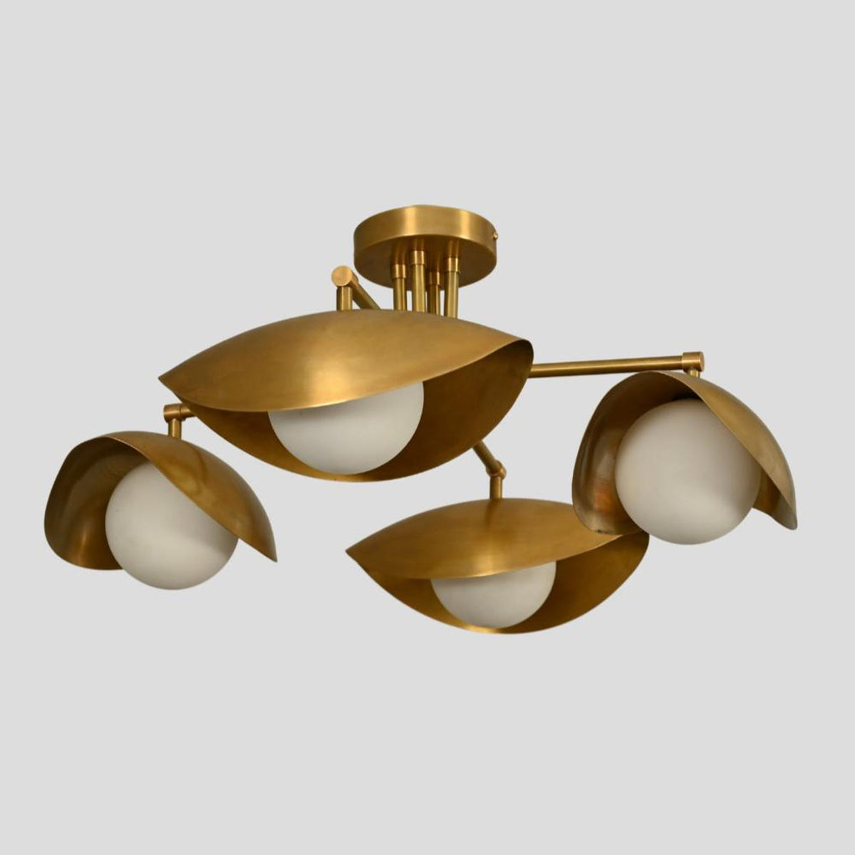 Angled view of modern industrial brass chandelier with three bowl-shaped brass shades and round glass globes.