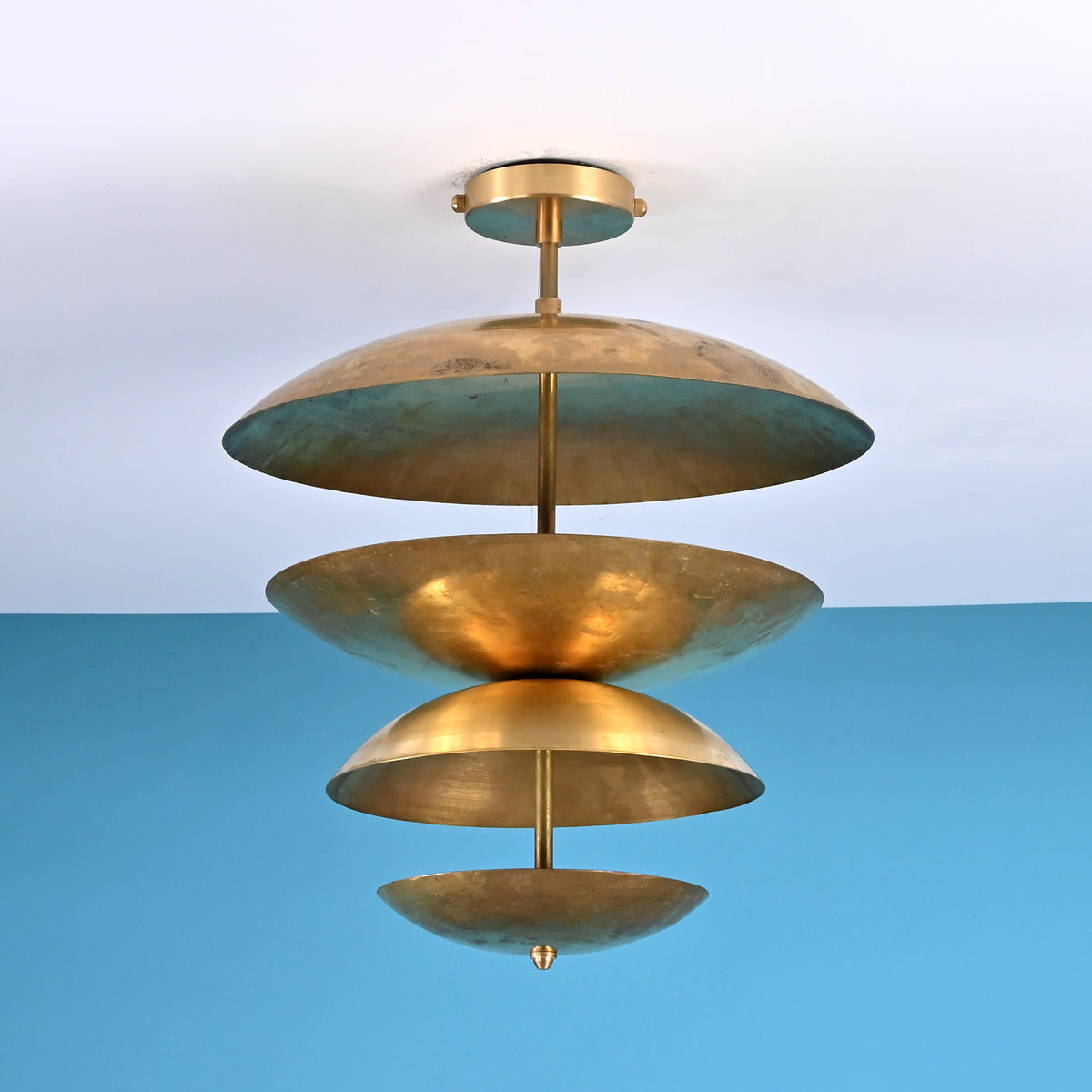 Sculptural layered brass ceiling light featuring stacked bowl-shaped discs in a modern industrial flush mount profile.