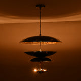 Modern multi-tier brass disc chandelier producing warm indirect light and sculptural glow