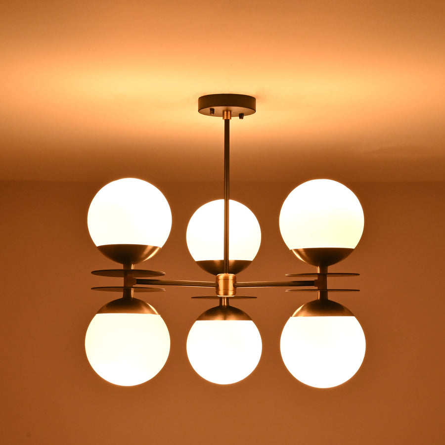 Brushed brass chandelier with six opal glass globes providing warm ambient lighting