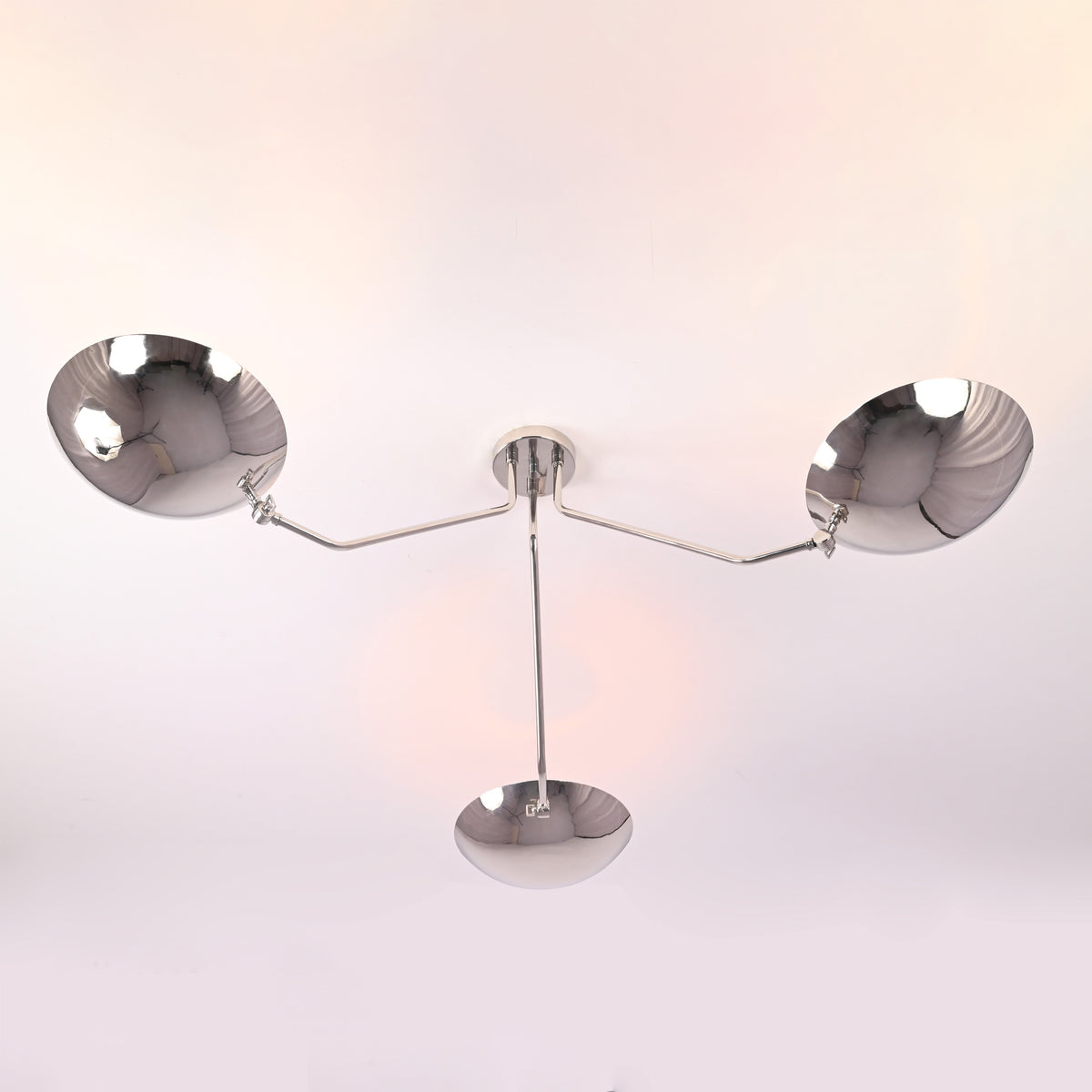 Bottom view of modern polished chrome ceiling light with three symmetrical brass bowl shades.