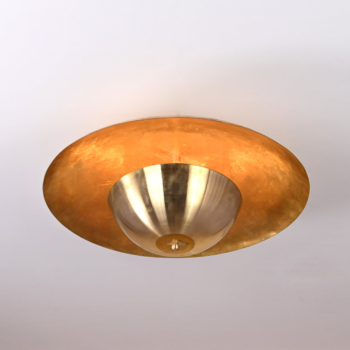 Modern raw brass flush mount ceiling light glowing with ambient golden illumination, handcrafted by Brass Leaf Studio