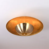 Modern raw brass flush mount ceiling light glowing with ambient golden illumination, handcrafted by Brass Leaf Studio