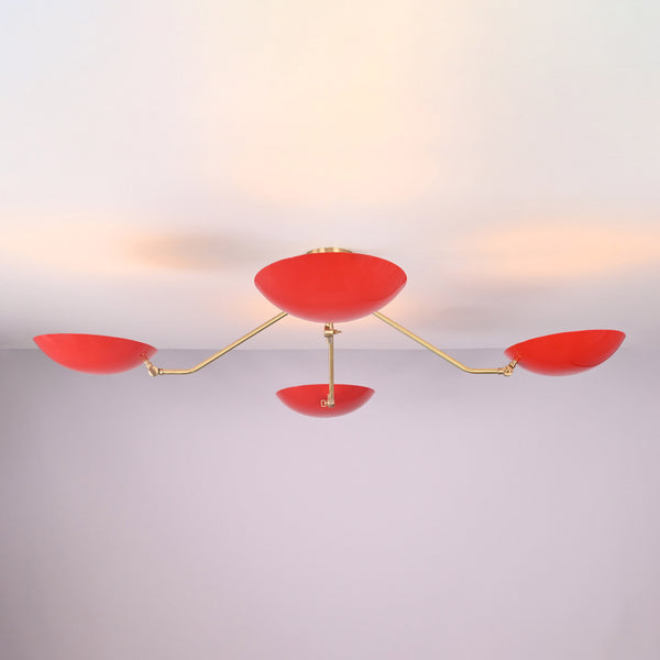 Angled view of modern red disc chandelier highlighting solid brass craftsmanship and minimalist industrial design.