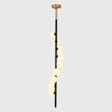 Modern stairwell globe chandelier shown from side angle with staggered round shades and tall vertical profile