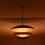 Modern tiered pendant light closeup showing sculptural layered discs and warm illuminated diffuser detail