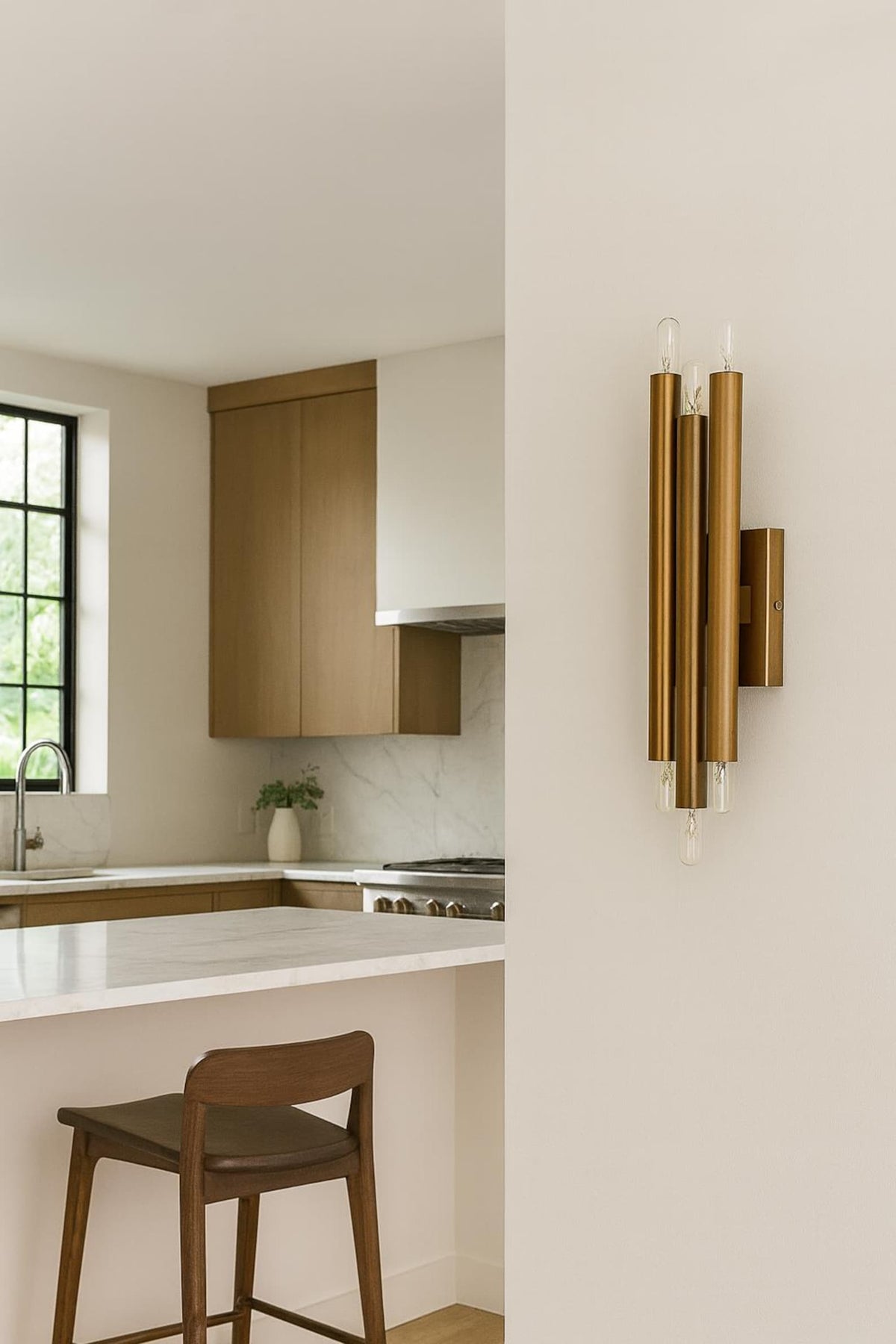 Modern vertical brass wall sconce with six exposed bulbs installed in contemporary kitchen interior creating architectural statement lighting