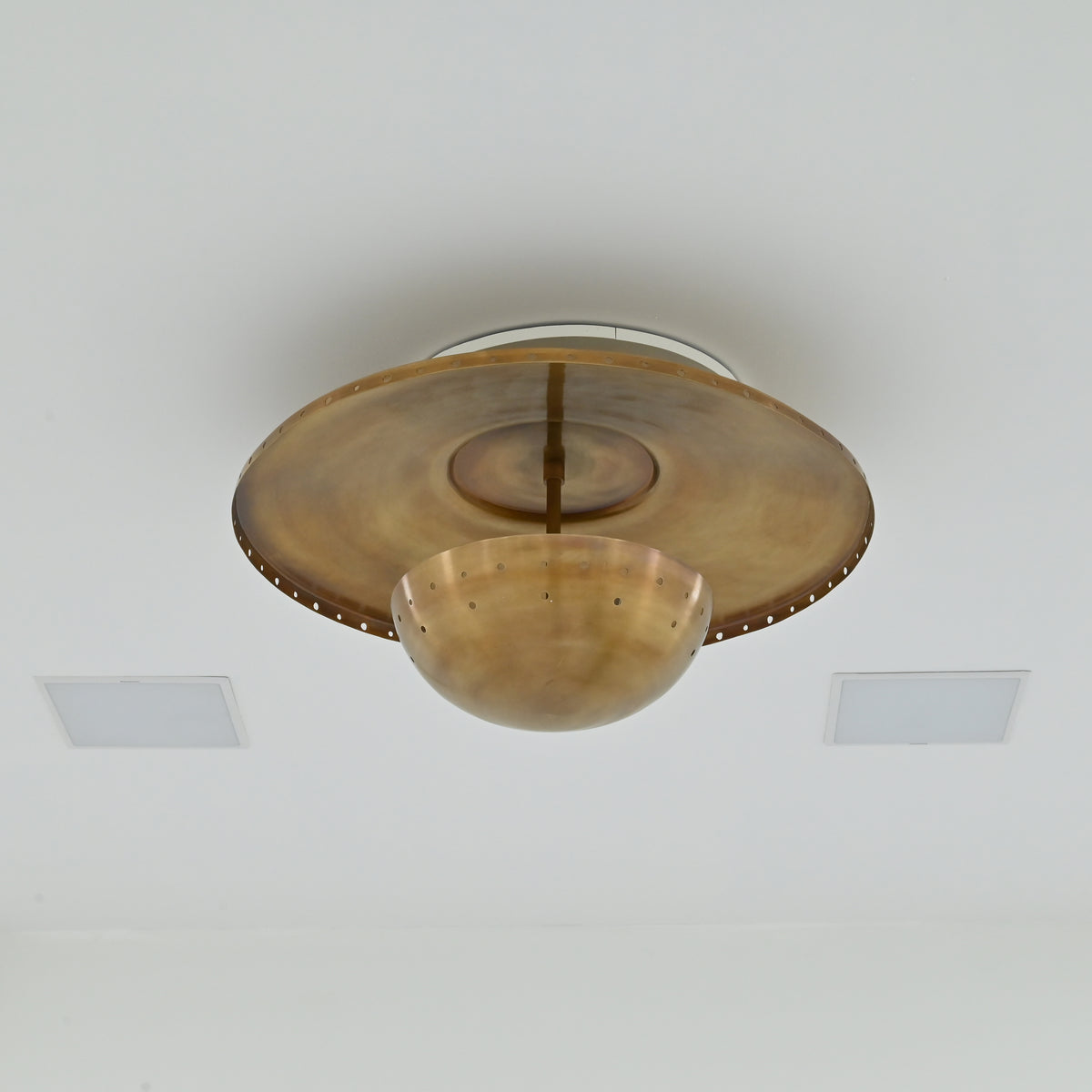 Mid century inspired brass ceiling light with low-profile design, perforated disc and decorative lower bowl