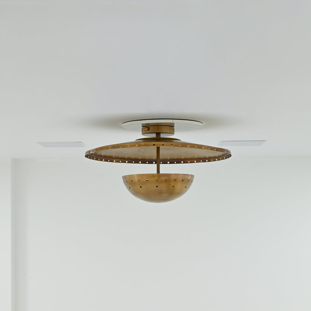 Illuminated Mykonos perforated brass flush mount casting warm decorative light and patterned ceiling shadows