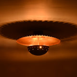 Close view of Mykonos ceiling light showing perforated detailing, brass patina finish and layered sculptural form