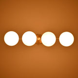 Opal glass globe shades on a brass linear chandelier glowing softly in a dark interior environment.