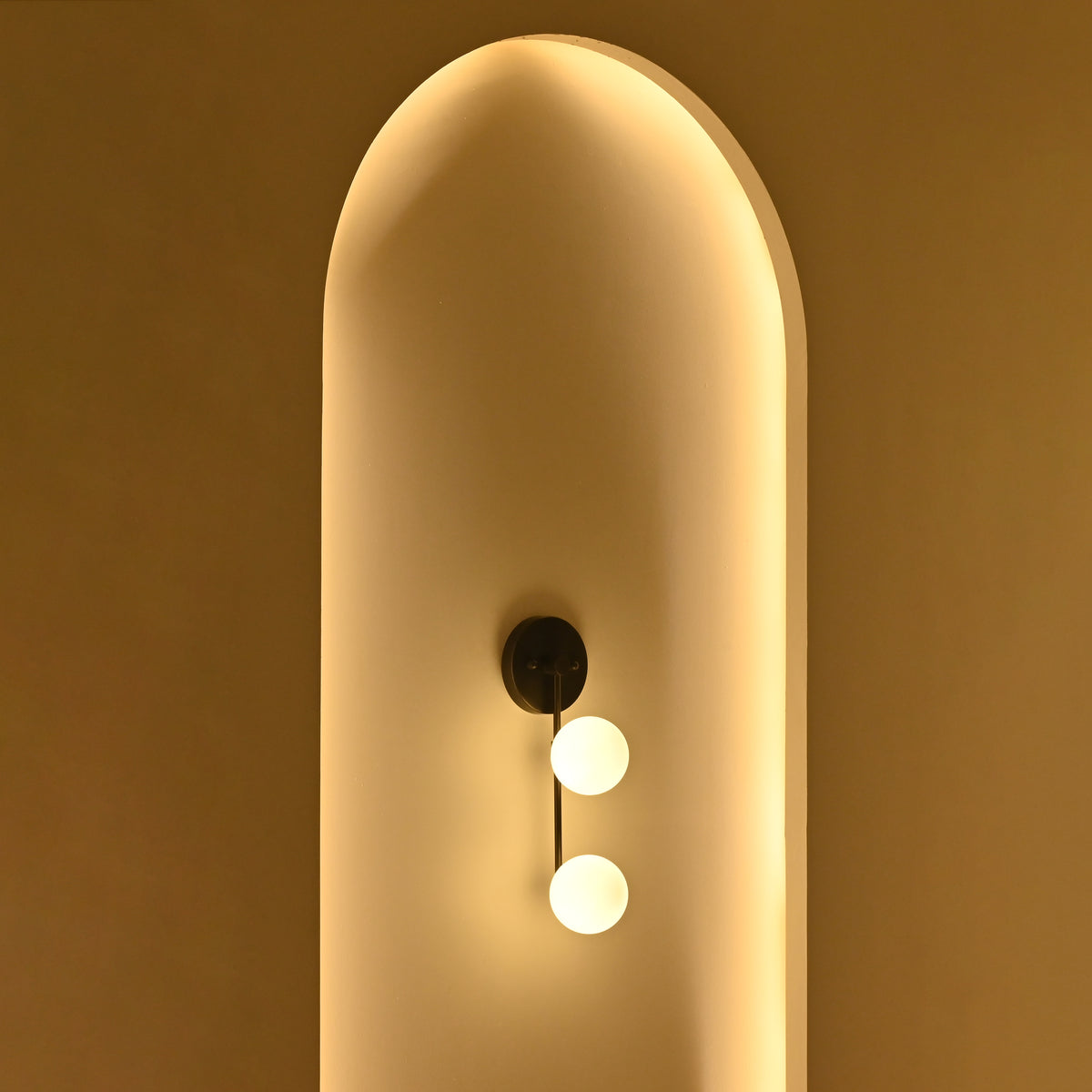 Opal globe bedside wall light with two softly glowing spherical shades positioned along a slim vertical stem