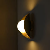 Opal globe wall light with curved brass shield and round wall canopy shown from side angle