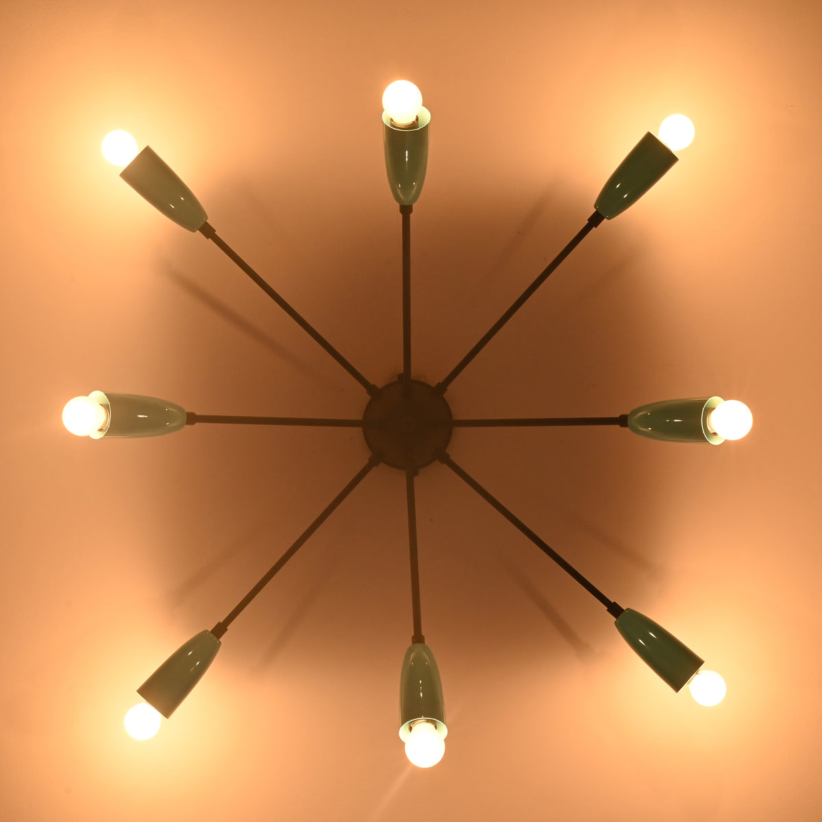 Orbit-style brass flush mount chandelier casting warm ambient light across the ceiling