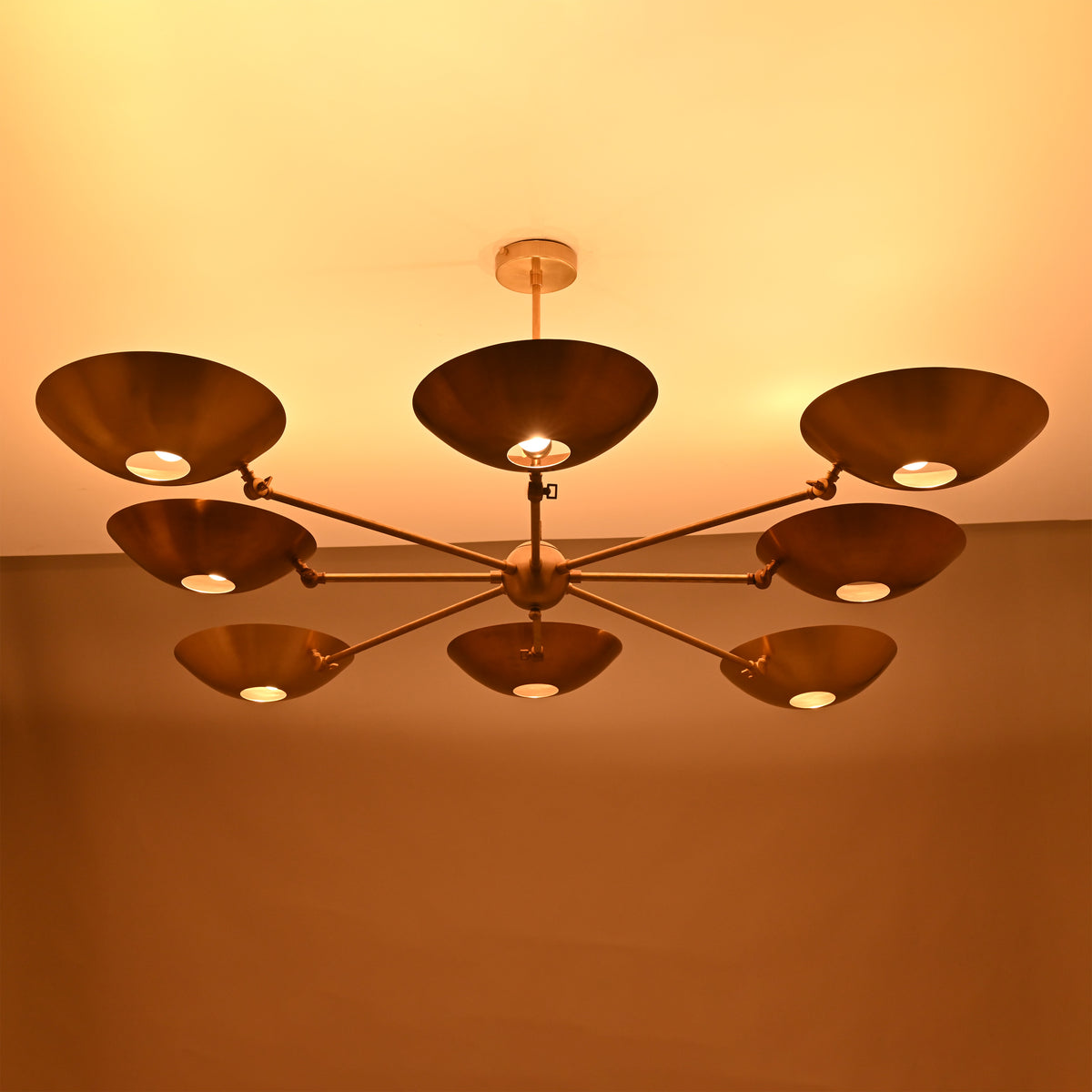 Angled perspective of 8-arm brass chandelier with modern bowl discs and sleek drop rod