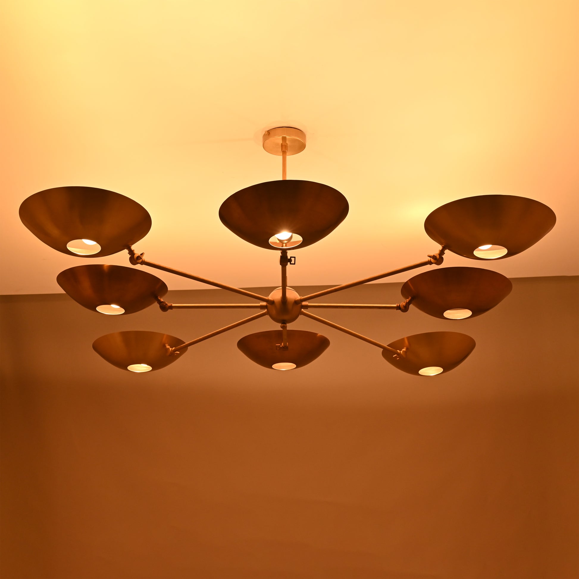 Angled perspective of 8-arm brass chandelier with modern bowl discs and sleek drop rod