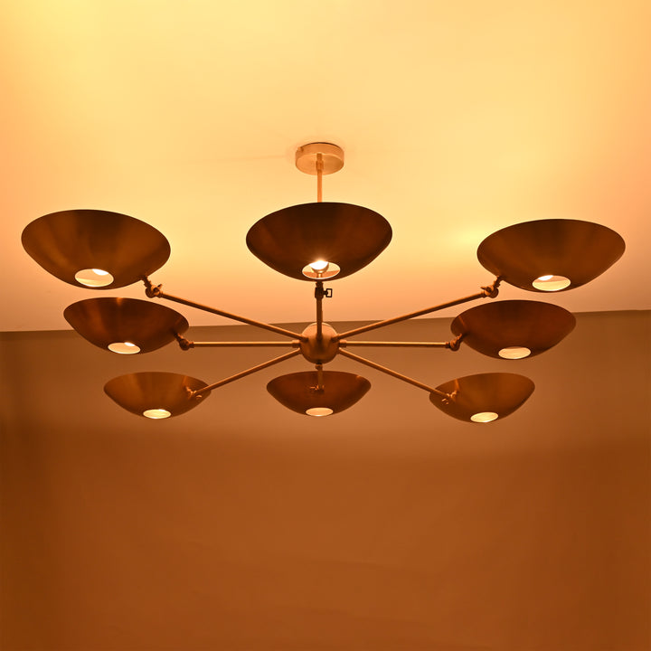 Angled perspective of 8-arm brass chandelier with modern bowl discs and sleek drop rod