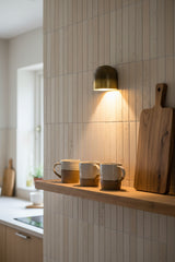 Patina brass accent wall light with small sculptural dome and soft warm wall wash effect