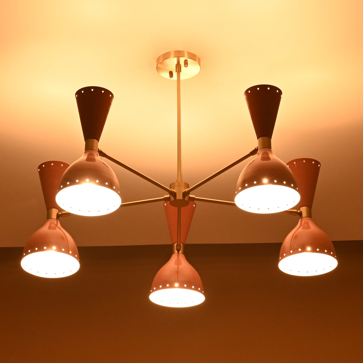 Warm illuminated view of mid-century peach brass chandelier showcasing soft ambient lighting