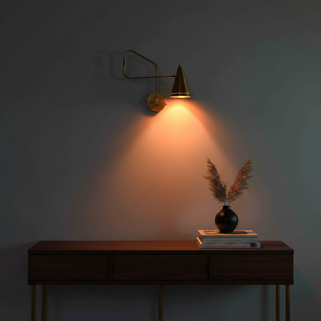 Perforated brass cone shade sconce with warm light detail and solid brass swing arm design