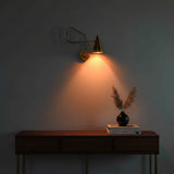 Perforated brass cone shade sconce with warm light detail and solid brass swing arm design