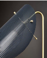 Close-up of perforated metal shade on handcrafted brass wall lamp showing fine detailing