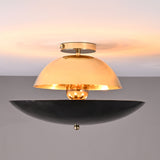 Front view of mixed-finish brass flushmount light with polished brass dome and blackened lower bowl, creating warm indirect illumination.