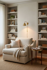 Polished brass downlight wall sconce with open cone shade directing warm illumination onto the wall below