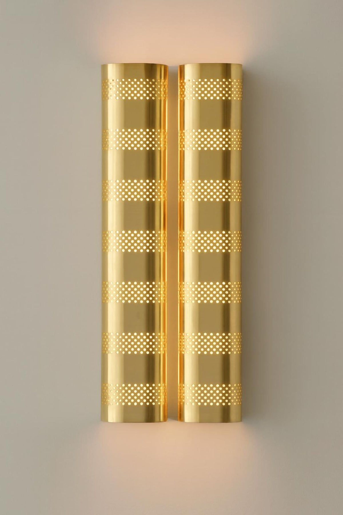 Polished brass modern wall sconce with perforated metal shade and warm ambient lighting