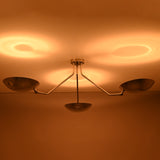 Three light polished chrome ceiling fixture highlighting symmetrical bowl shaped shades and warm glow.