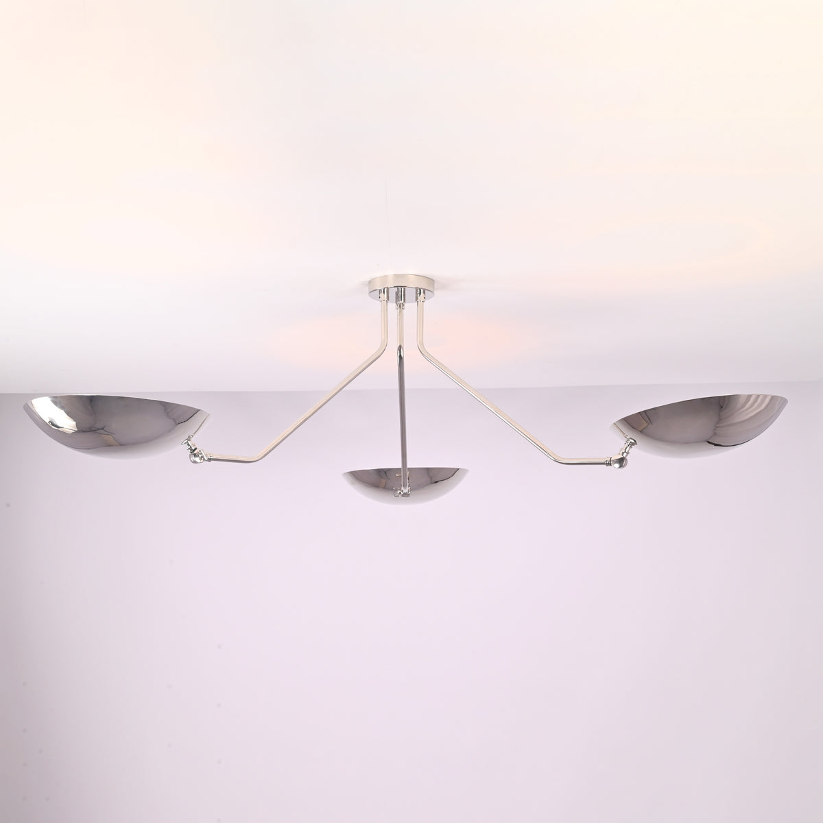 Angled view of polished chrome semi flush mount ceiling light featuring three sculpted brass bowl shades.