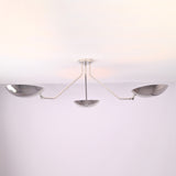Angled view of polished chrome semi flush mount ceiling light featuring three sculpted brass bowl shades.
