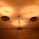 Polished chrome ceiling light casting warm indirect ambient lighting through three brass bowl shades.