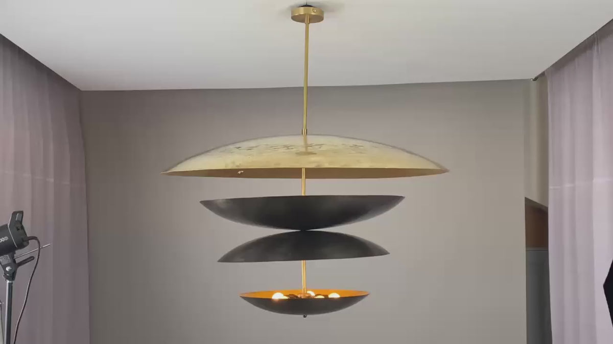 Modern tiered chandelier featuring a layered design with matte black and antique gold dome-shaped discs, suspended from a gold rod, perfect for adding elegance and visual intrigue to contemporary interiors.