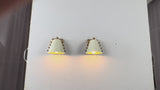 Set of two white shade wall sconces by Brass Leaf Studio shown with warm downward glow, decorative side details, and elegant styling for bedroom, bathroom, hallway, and entryway interiors