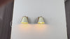 Set of two white shade wall sconces by Brass Leaf Studio shown with warm downward glow, decorative side details, and elegant styling for bedroom, bathroom, hallway, and entryway interiors