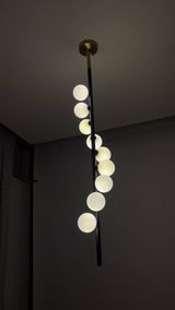 Modern 9-light globe pendant chandelier video showing vertical cascading opal shades, warm ambient glow, black rod, brass-tone canopy, and luxury interior installation