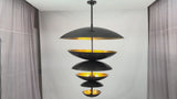 Video showing the Aureon 13-light six tier solid brass disc chandelier with blackened brass outer surfaces, brushed brass interiors, and warm layered glow in luxury interiors