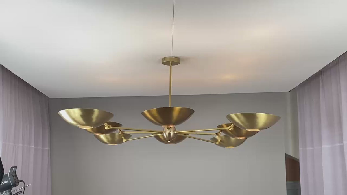 Wide brass chandelier glowing softly with upward and downward lighting for ambient elegance