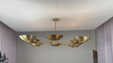 Wide brass chandelier glowing softly with upward and downward lighting for ambient elegance