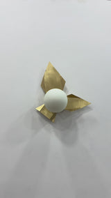 Brussels brass leaf glass globe wall sconce video showing raw brass folded leaf design, glowing round globe, warm wall reflection, and sculptural decorative lighting