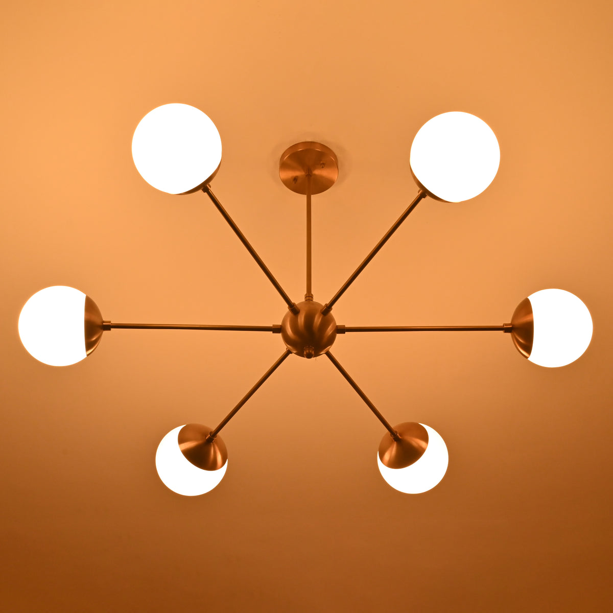 Underside view of 6-light brass chandelier radiating warm illumination through opal glass globes.