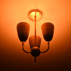 Detailed view of three cone-shaped brass shades connected to brass ceiling base